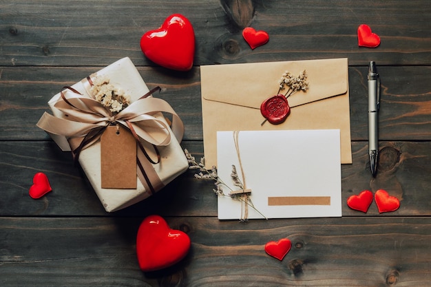 Caja de regalo y tarjeta de felicitación con cinta de lazo y corazones de papel en la mesa de madera para el día de San Valentín. copie el espacio