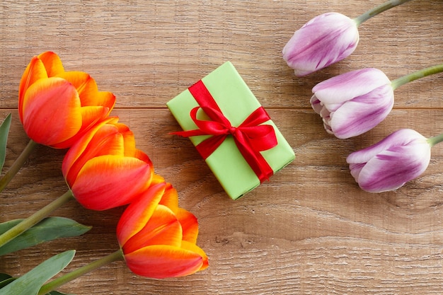 Caja de regalo con tulipanes rojos y lilas sobre tablas de madera Concepto de tarjeta de felicitación Vista superior