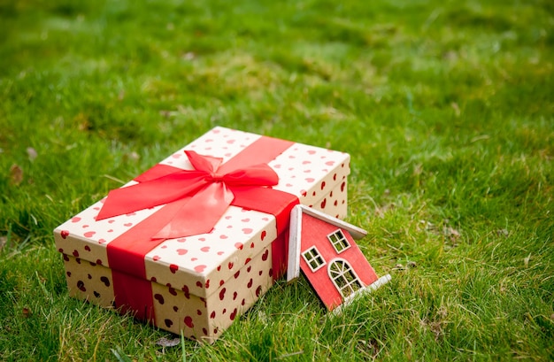 Caja de regalo de vacaciones y casita de juguete sobre la hierba verde