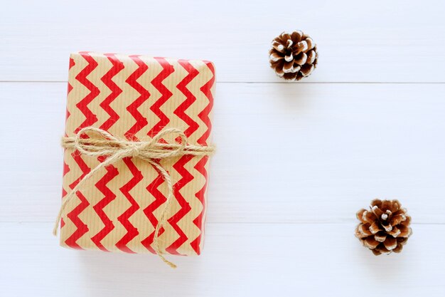 Caja de regalo vintage marrón y rojo y ornamento sobre fondo blanco de madera