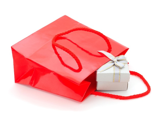 Una caja de regalos sale de una bolsa de papel aislada sobre un fondo blanco