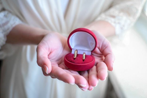 Foto caja roja con anillos de bodas de oro en manos de la novia closeup