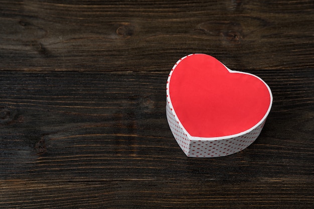 Foto caja roja en forma de corazón sobre la mesa de madera marrón. vista superior. regalo para el día de san valentín. espacio para texto