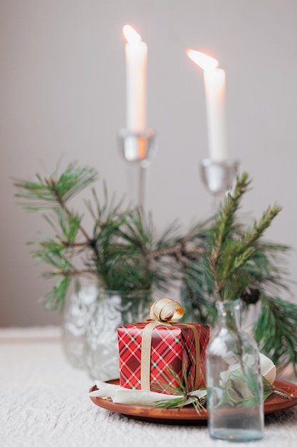 Una caja roja con un regalo y una cinta dorada velas en el fondo decoración festiva de árboles de Navidad