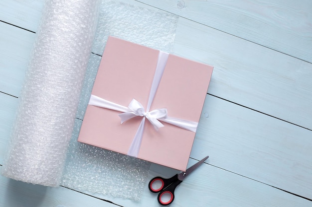 Caja rosa con lazo blanco sobre fondo de madera embalaje de regalo