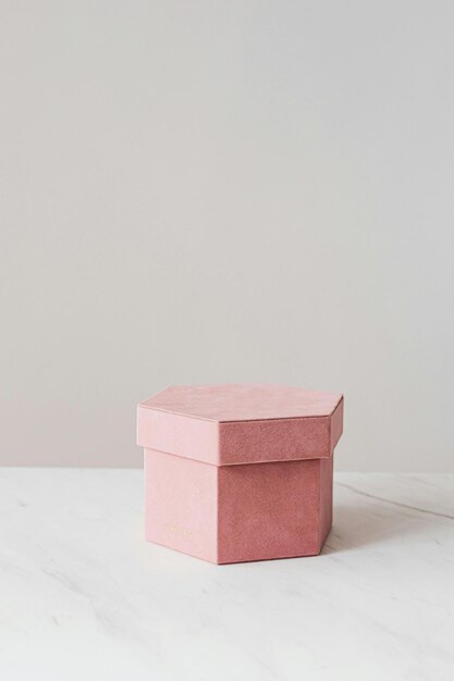 una caja rosa con una parte superior blanca se sienta en una mesa de mármol blanco