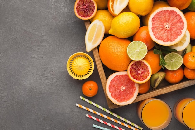 Caja con surtido de cítricos sobre fondo gris, espacio de copia. Vista superior de naranjas, limones, mandarinas y otras frutas exóticas, endecha plana. Hacer un concepto de frescura de desintoxicación y una maqueta de recetas.