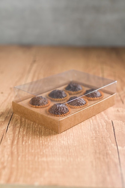 Caja transparente llena de Sweet Brigadeiro brasileño sobre un escritorio de madera Versión vegana