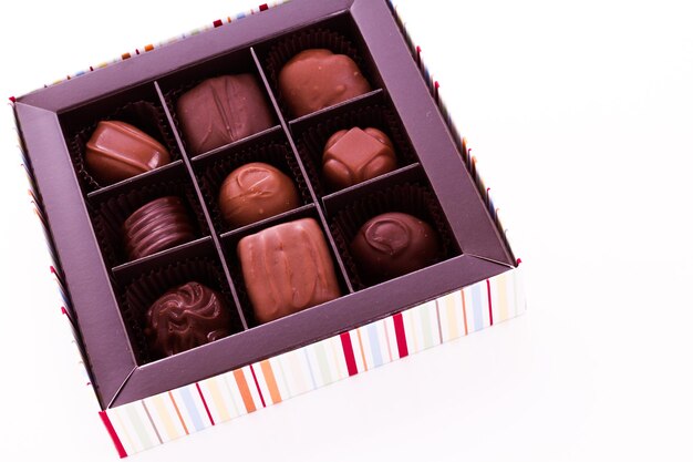 Caja de trufas gourmet surtidas sobre un fondo blanco.