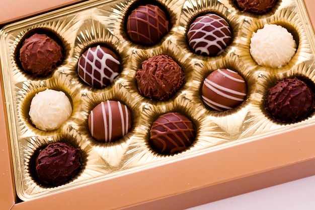 Caja de trufas gourmet surtidas sobre un fondo blanco.