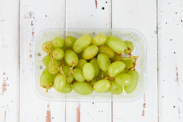 Una caja de uvas verdes sin semillas envasadas en una caja de plástico transparente