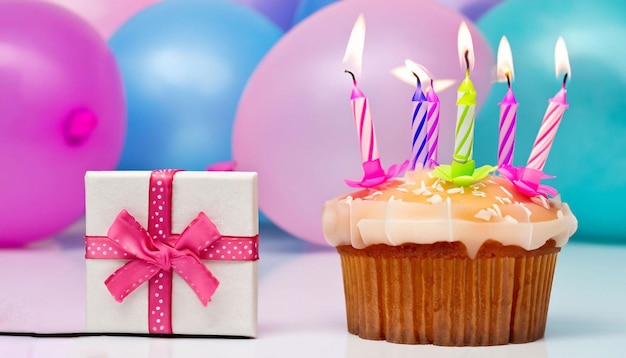 Una caja de velas de cumpleaños junto a una magdalena con una caja de regalo delante.