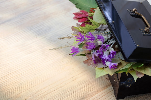 Caja vintage con hojas de otoño y flores silvestres dentro.