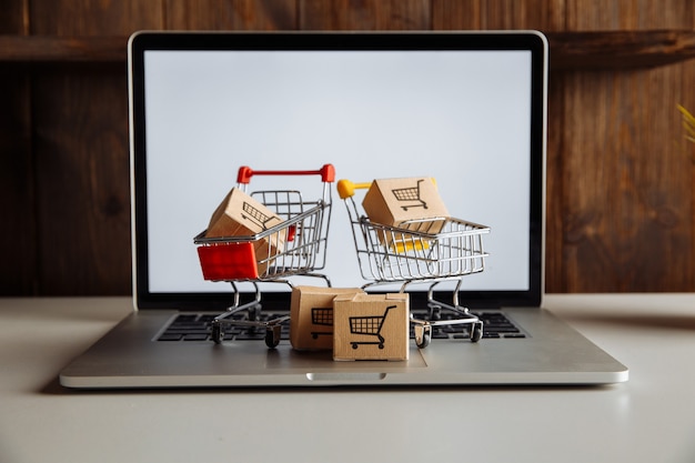 Foto cajas en un carrito en un teclado de computadora portátil. concepto de compra online.