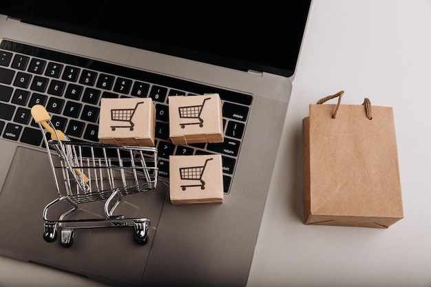 Cajas de cartón con un carrito en un teclado y servicio de compras de bolsas de compras en la web en línea