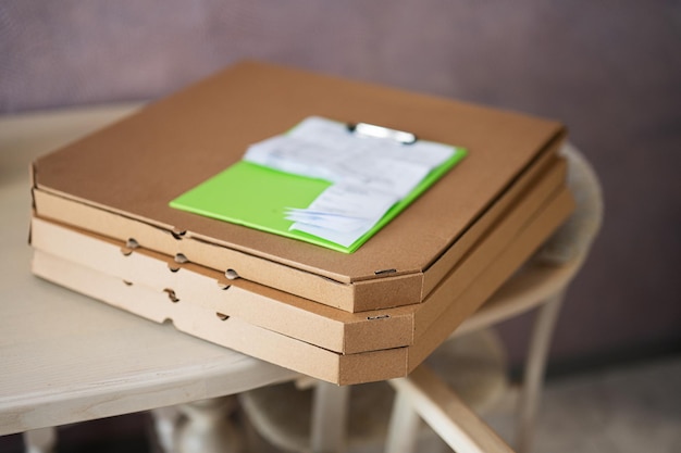 Cajas de cartón para pizza con portapapeles de entrega en la cocina en la mesa