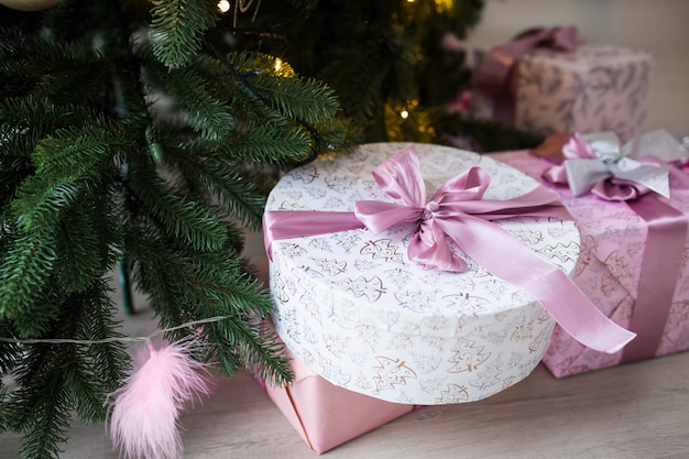 Cajas de color rosa con regalos bajo un árbol de Navidad. Luz diurna luz brillante.