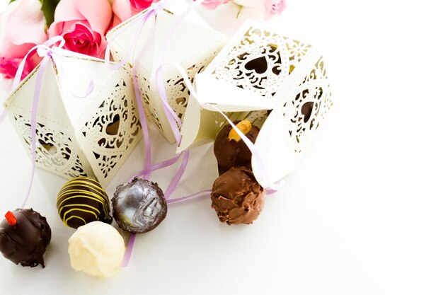 Cajas decorativas cuadradas de encaje blanco con forma de corazón rellenas de trufas gourmet.