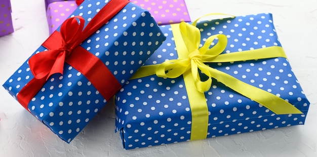 Cajas embaladas en papel azul festivo y atadas con cinta de seda sobre fondo blanco, regalo de cumpleaños, sorpresa, cerrar