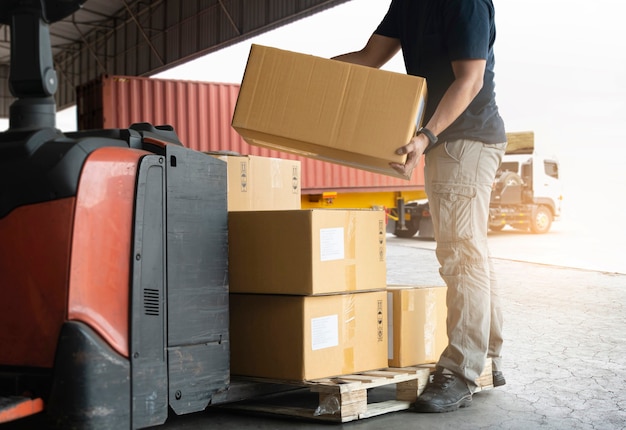 Cajas de envío. Trabajador de Warhouse levantando cajas de cartón apiladas sobre palés.