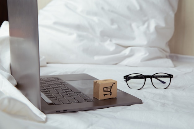 Cajas de papel o paquete en un teclado de computadora portátil en el dormitorio. Servicio de compra en la web online y ofrece entrega a domicilio.