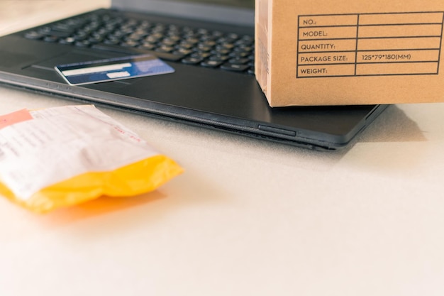 Foto cajas de papel y tarjeta de crédito en el teclado de un concepto de compra en línea de una computadora portátil
