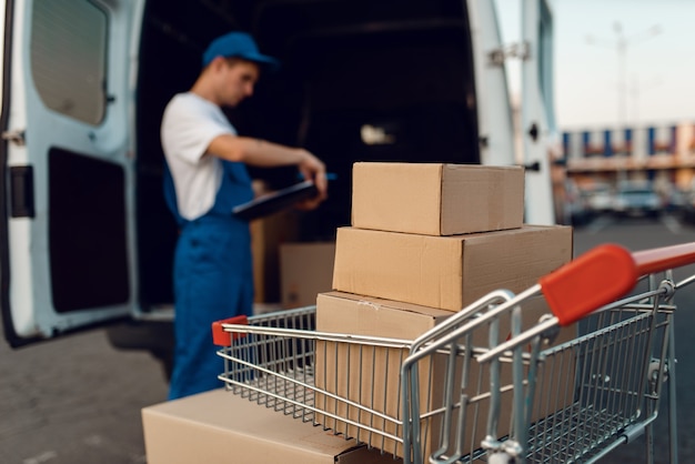 Cajas de paquetería y cuaderno en carro de carga, concepto de servicio de entrega, entrega de negocios, nadie. Paquetes de cartón, trabajo de entrega, mensajería o envío