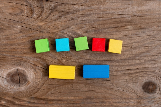 Cajas rectangulares de cubo de muestra pulidas con varios colores que simbolizan el desarrollo del crecimiento de la estabilidad alineadas en la superficie con diferentes perspectivas delimitadas por accesorios de suministros electrónicos