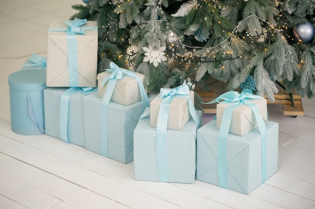 Cajas de regalo bajo el árbol de Navidad sobre un piso de madera blanca