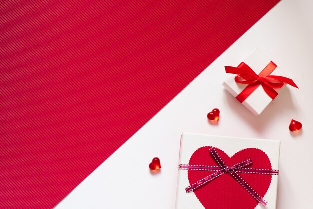 Cajas de regalo con arcos y corazones sobre fondo rojo y blanco. Pensamiento creativo sobre el amor y el día de San Valentín