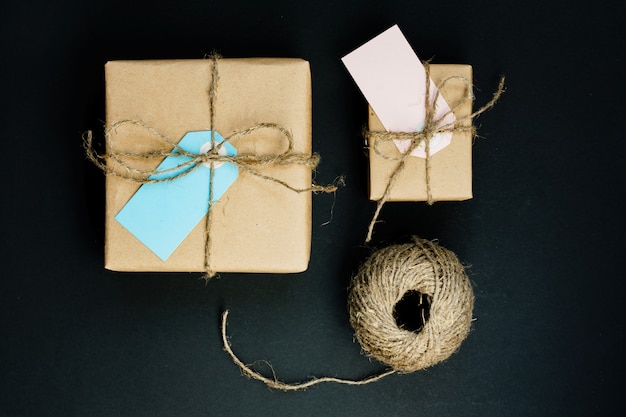 Cajas de regalo artesanales envueltas en papel artesanal con etiqueta de tarjeta de papel azul y rosa, cuerda y pinzas de madera para la decoración.