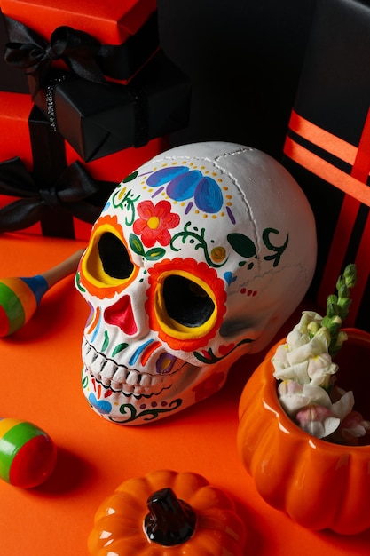 Cajas de regalo de calavera mexicana y calabaza con flores sobre fondo naranja