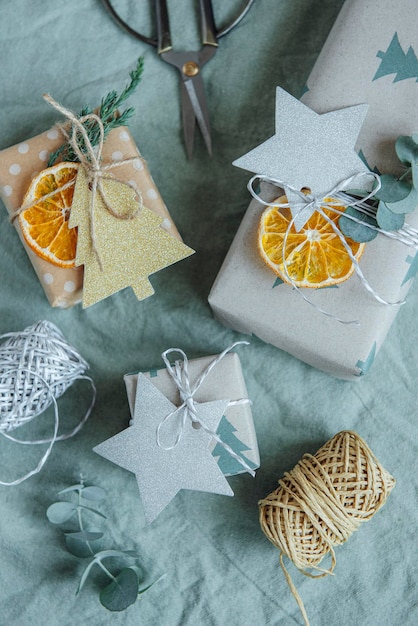 Cajas de regalo caseras decorativas navideñas envueltas en papel kraft marrón sobre un fondo verde textil