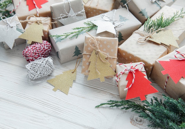 Cajas de regalo caseras decorativas navideñas envueltas en papel kraft marrón sobre una mesa de madera blanca