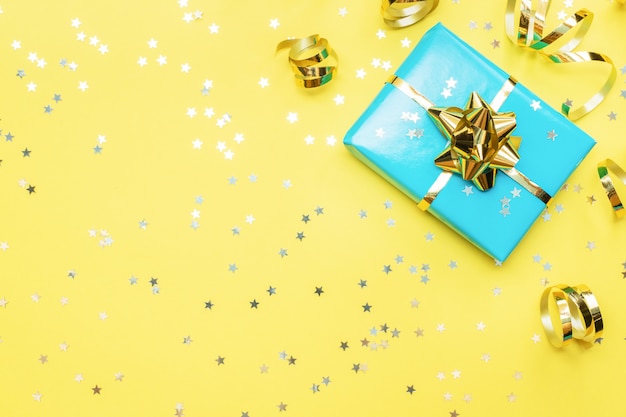 Cajas de regalo con cintas de oro y arcos, estrellas de confeti sobre un fondo amarillo. Copia espacio Lay Flat. Tarjeta de felicitación para fiesta de cumpleaños, día de la madre de la boda de Navidad.