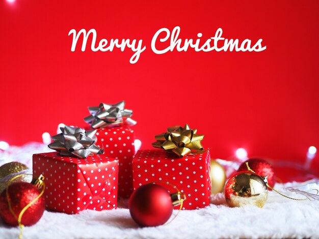 Cajas de regalo con decoración de bola de Navidad sobre fondo rojo