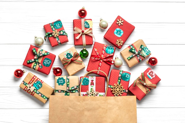Cajas de regalo envueltas a mano decoradas con cintas, copos de nieve y números en una mesa de madera blanca