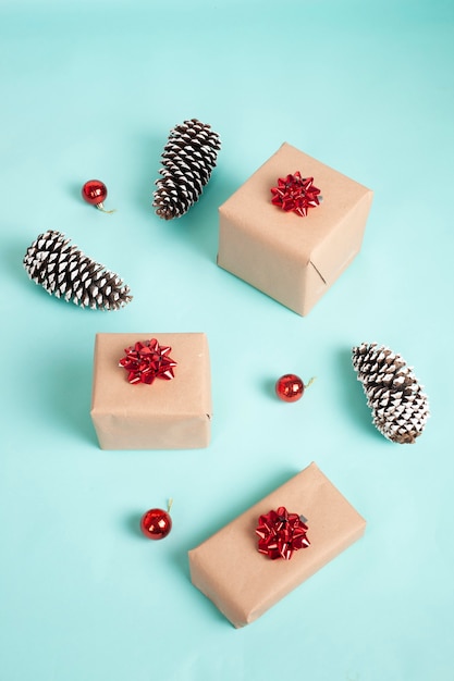 Cajas de regalo envueltas en papel kraft y atadas con lazo navideño rojo sobre fondo azul.