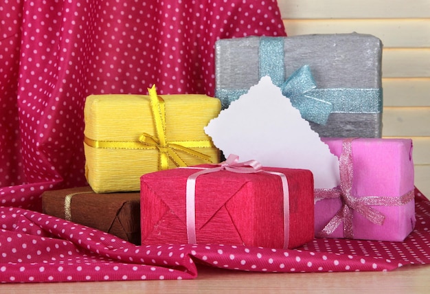 Cajas de regalo con etiqueta en blanco en la mesa sobre fondo de tela