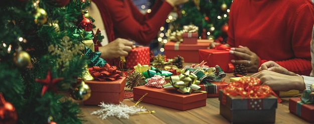 Cajas de regalo maravillosas con lazo encantador colorido en la mesa en la fiesta de la noche de Navidad. Las mujeres de la familia disfrutan dando regalos para compartir un cálido amor en felices fiestas. Agregue un poco de ruido para adaptarse a la imagen de estilo vintage.