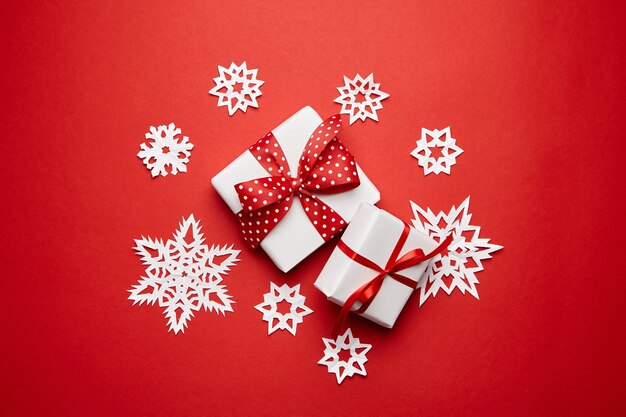 Cajas de regalo de Navidad con copos de nieve blancas sobre fondo rojo vista superior