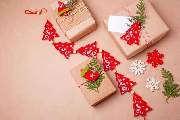 Foto cajas de regalo de navidad, guirnalda roja con árboles de navidad decorativos. estilo plano