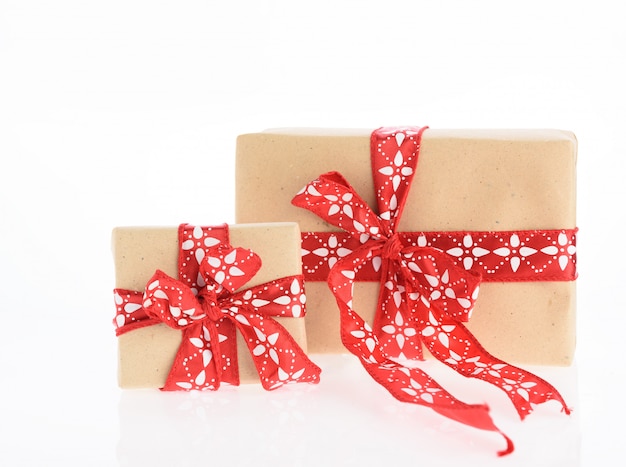 Foto cajas de regalo de navidad marrón envuelto con cinta roja aislado sobre fondo blanco.