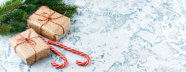 Cajas de regalo de Navidad, rama de abeto con conos, bastones de caramelo en la luz