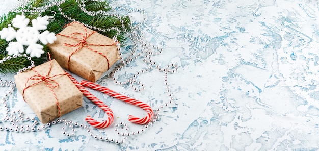Cajas de regalo de Navidad, rama de abeto con conos, bastones de caramelo en la luz