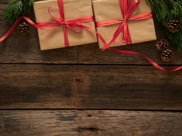 Cajas de regalo de Navidad con ramas de abeto y adornos sobre fondo rústico de madera oscura.
