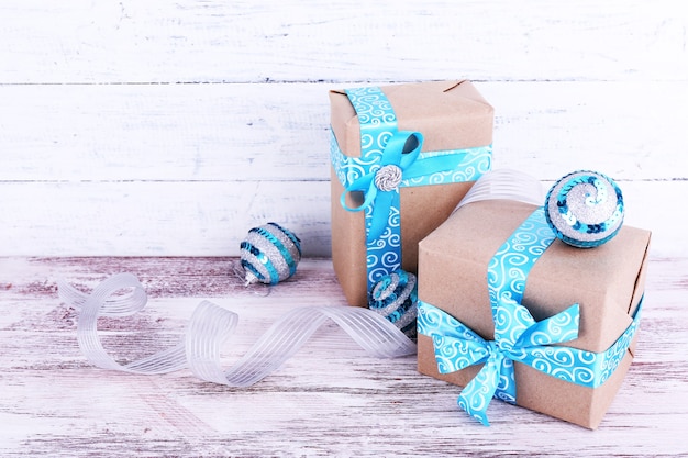 Cajas de regalo navideñas decoradas con cinta azul en la mesa sobre fondo de pared de madera