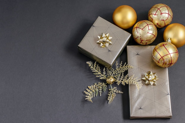 Cajas de regalo navideñas envueltas y bolas y adornos de color oro de la fortuna sobre el negro.