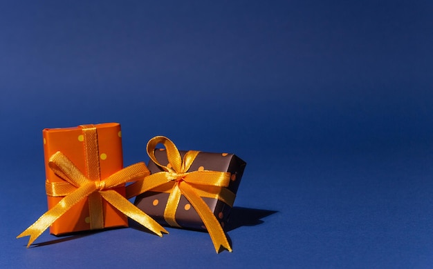 Foto cajas de regalo con papel de color con lunares atados con cinta amarilla sobre fondo azul. feliz navidad