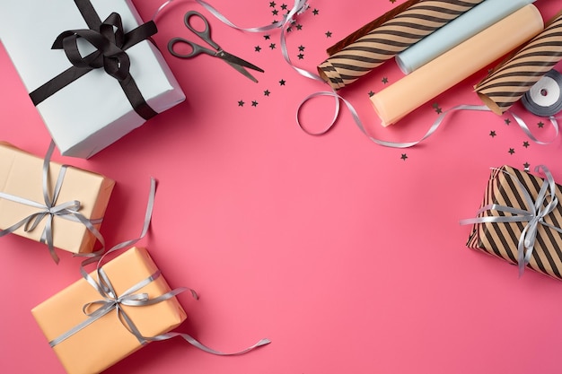 Cajas de regalo de papel rosa y blanco a rayas y marrón liso de diferentes tamaños atadas con r negro y plateado